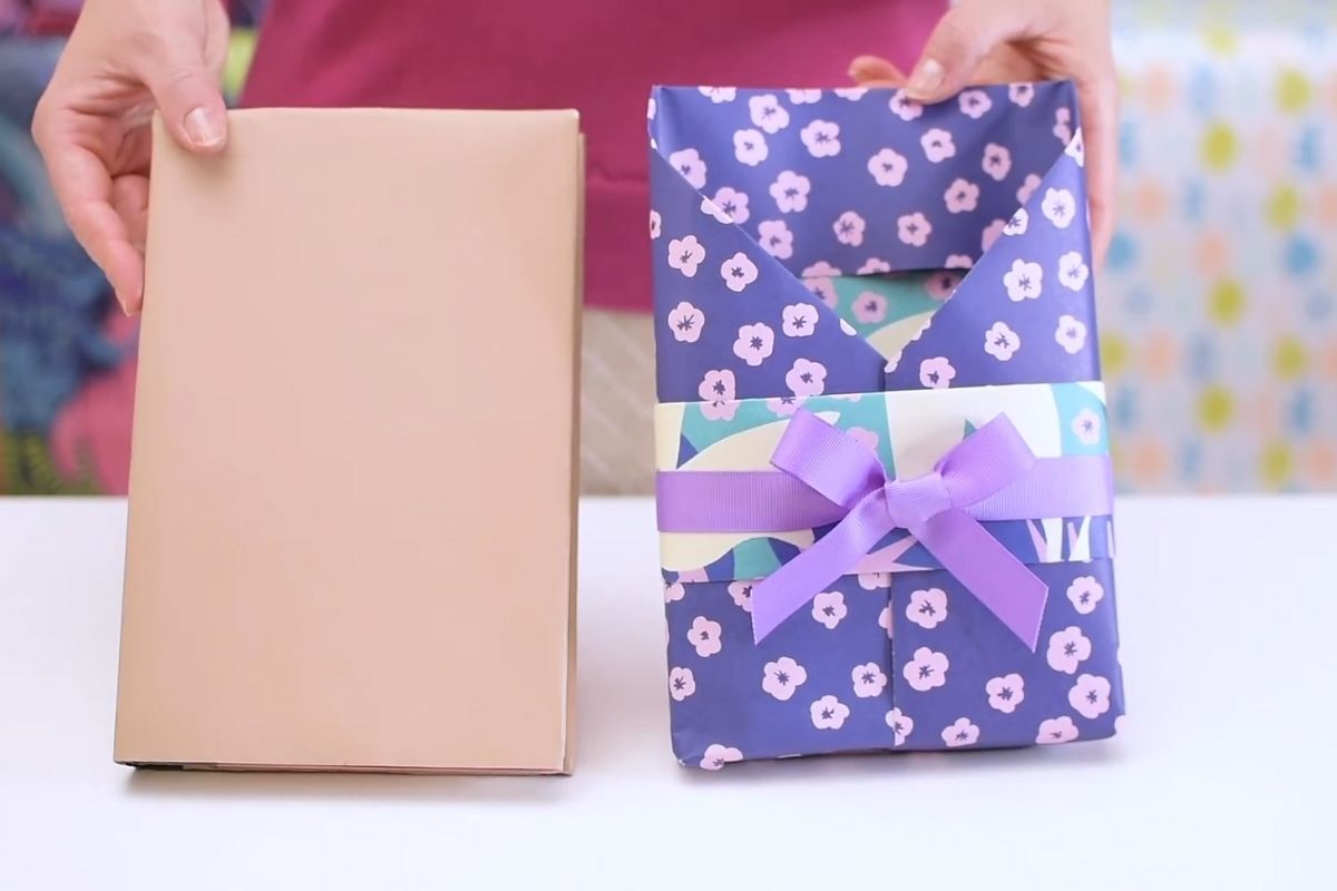 Ruke drze knjigu pored praznicno upakovane knjige sa masnom