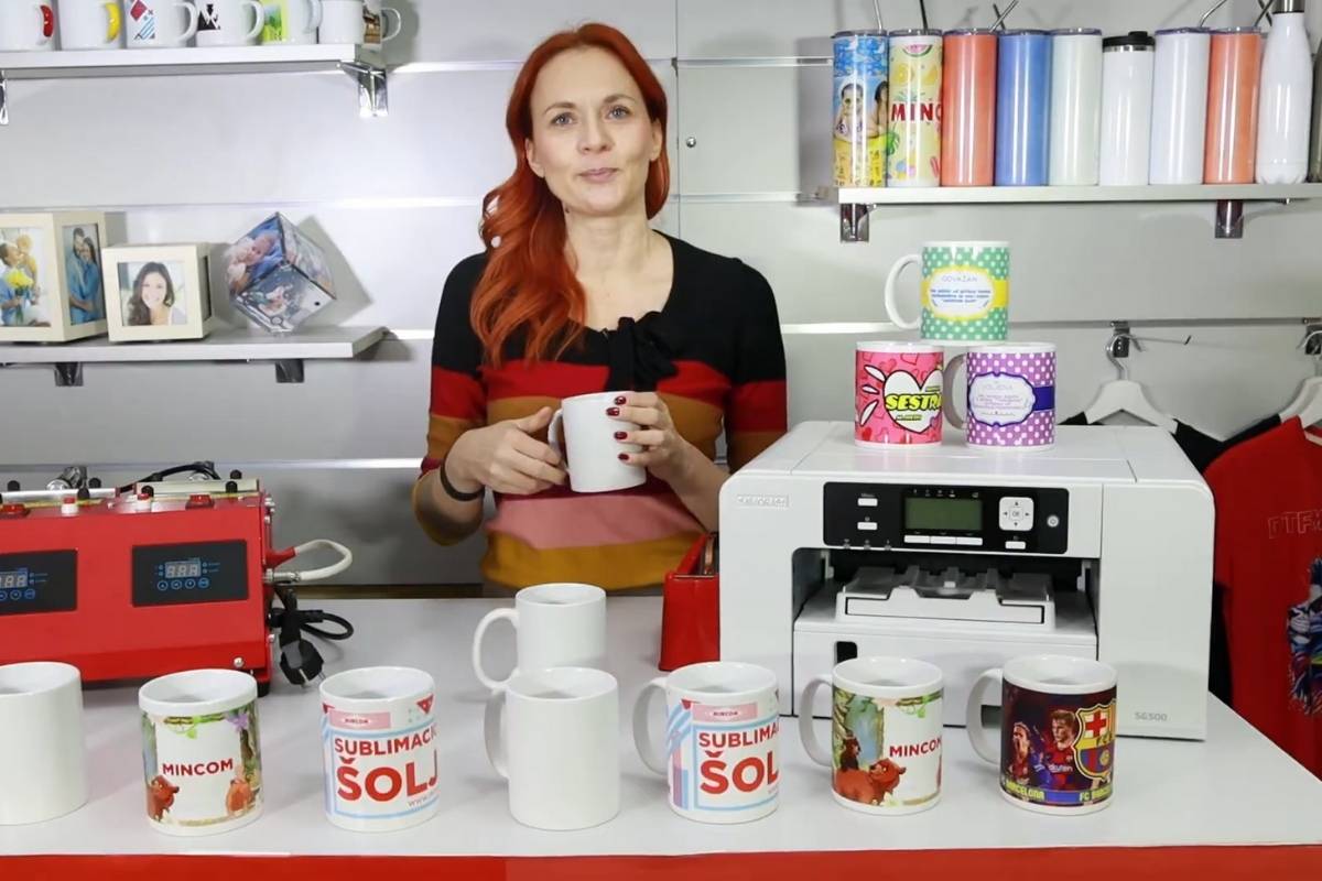 Zena u radionici drzi solju dok su na stolu izlozene personalizovane solje i oprema za sublimaciju