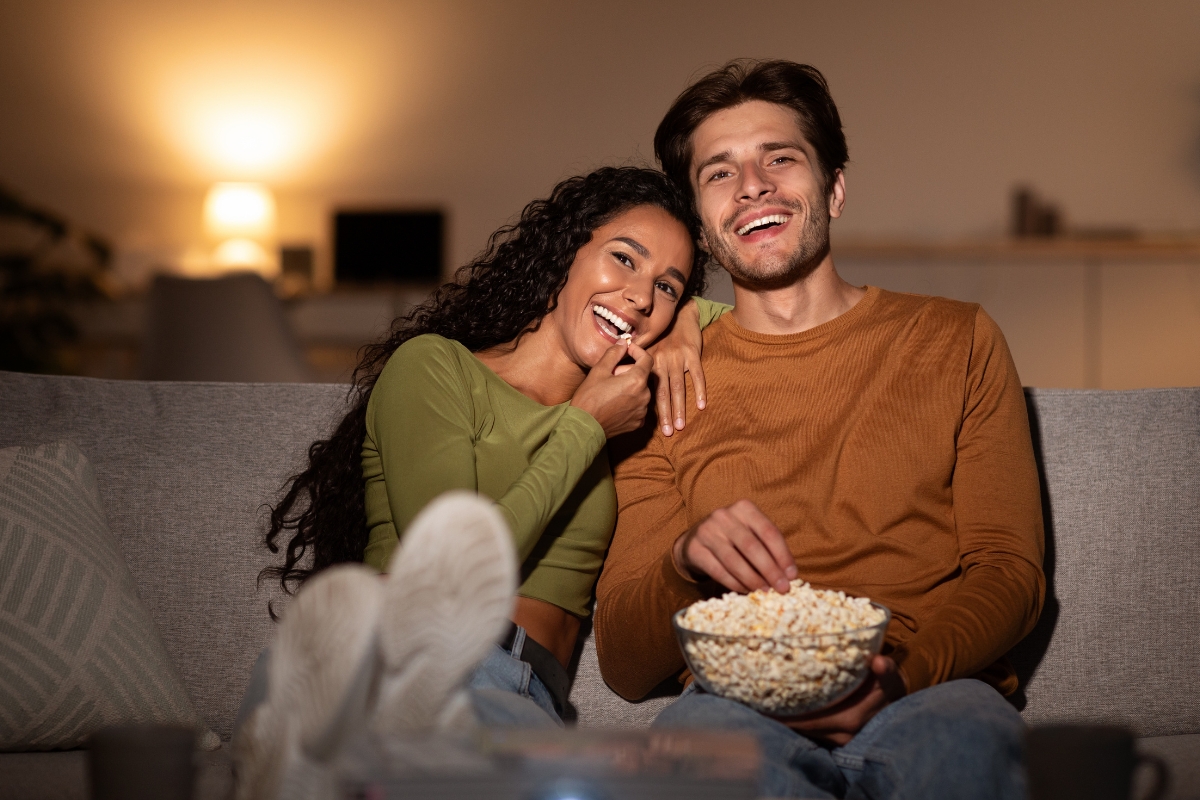 momak i devojka jedu kokice i smeju se dok gledaju film