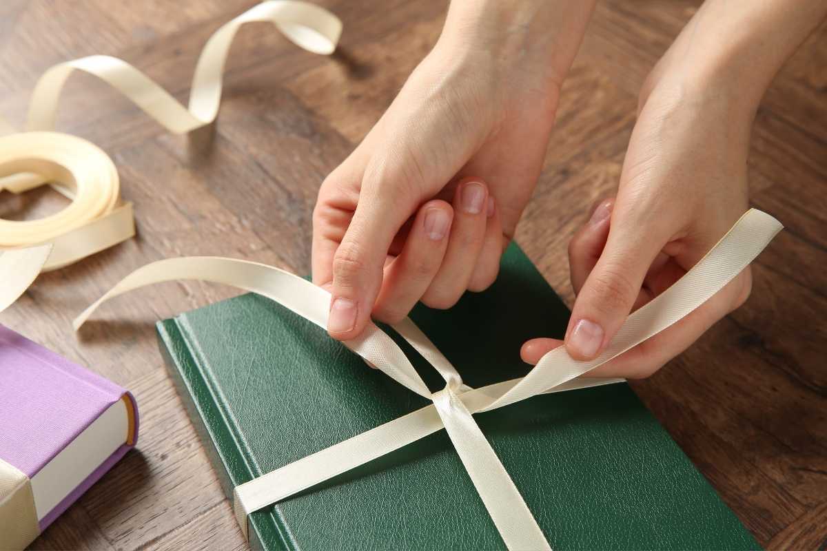 osoba vezuje mašnu na knjigu 